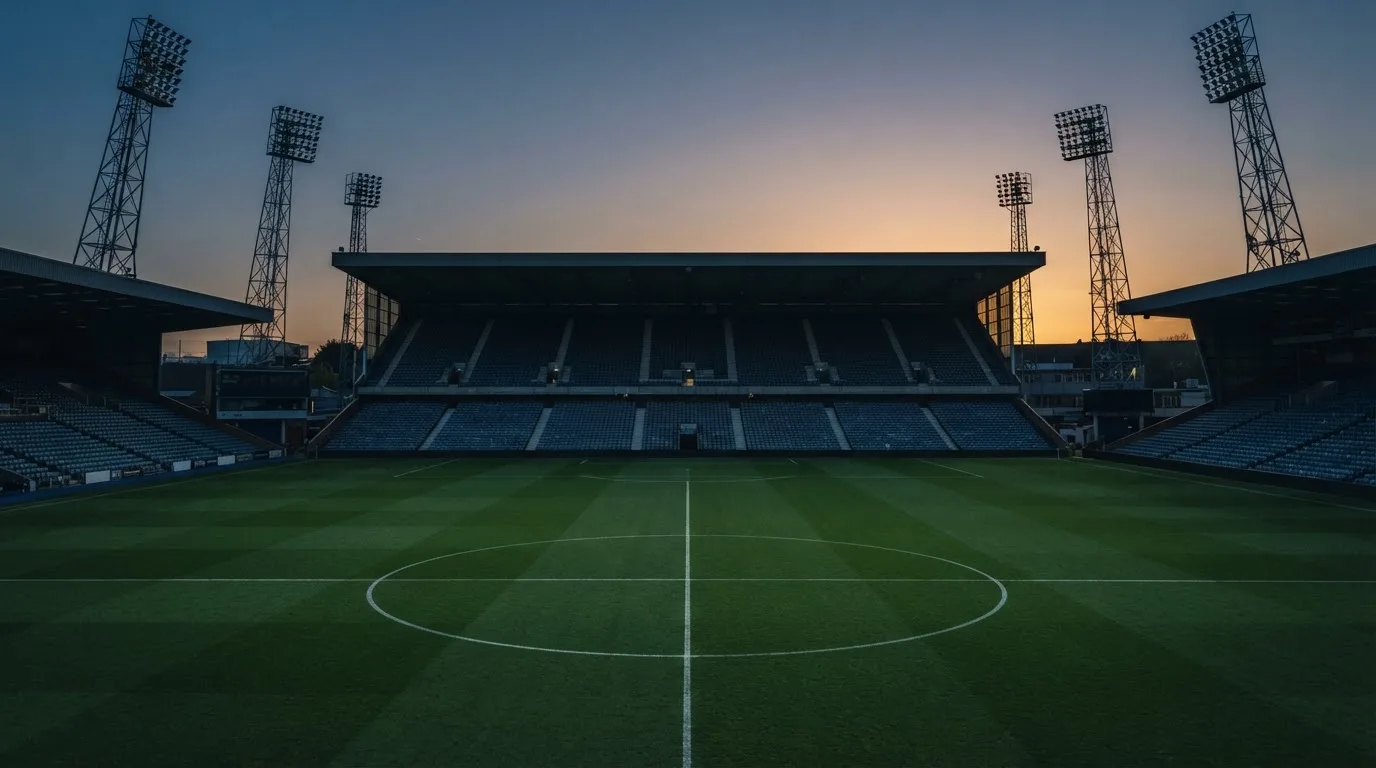 An empty football stadium with floodlight masts at dusk