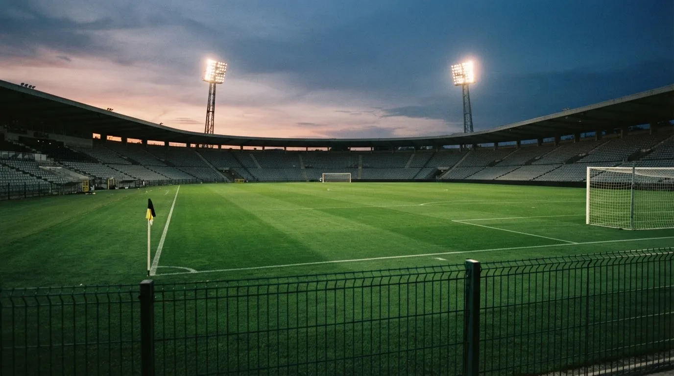 An empty football stadium with floodlight masts at dusk