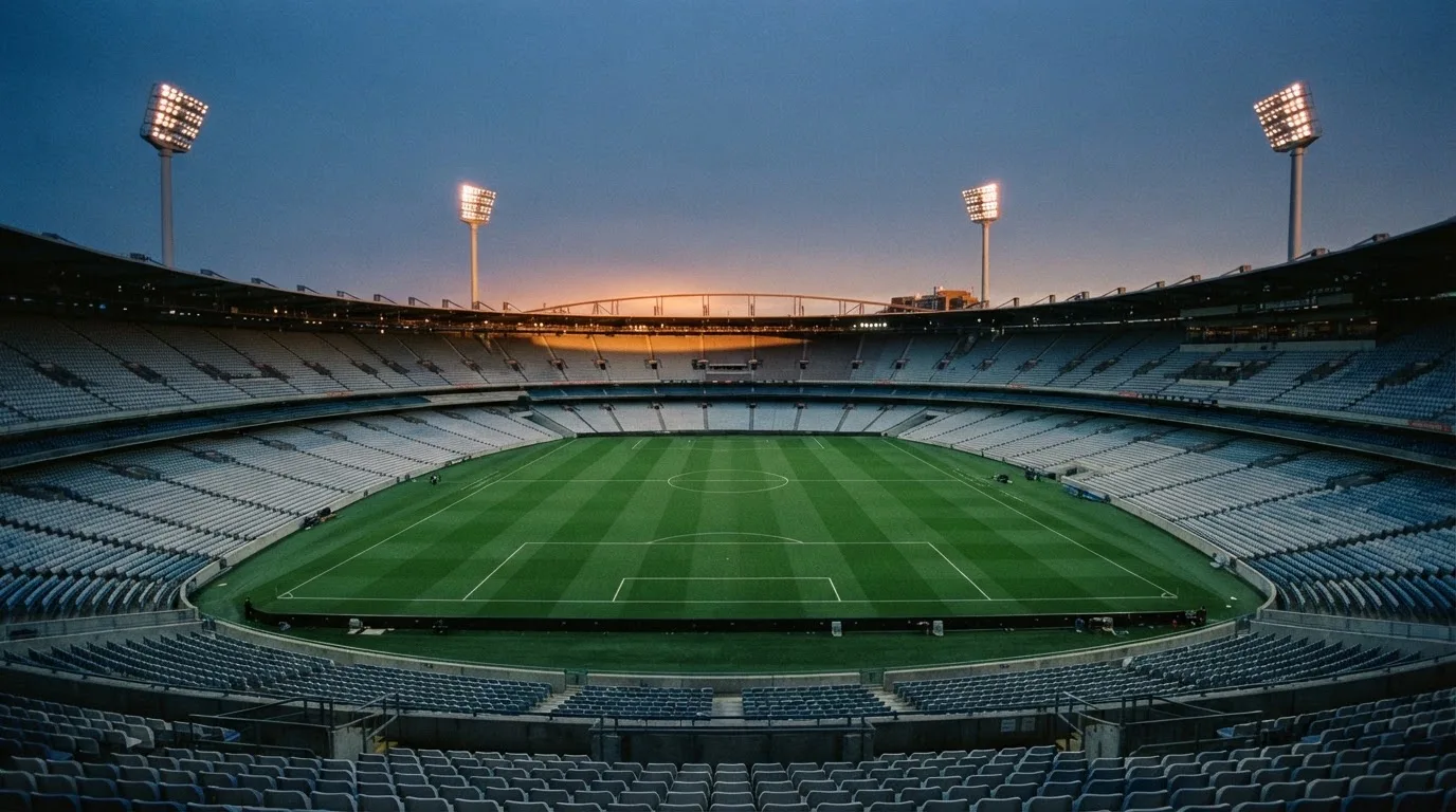 An empty football stadium with floodlight masts at dusk