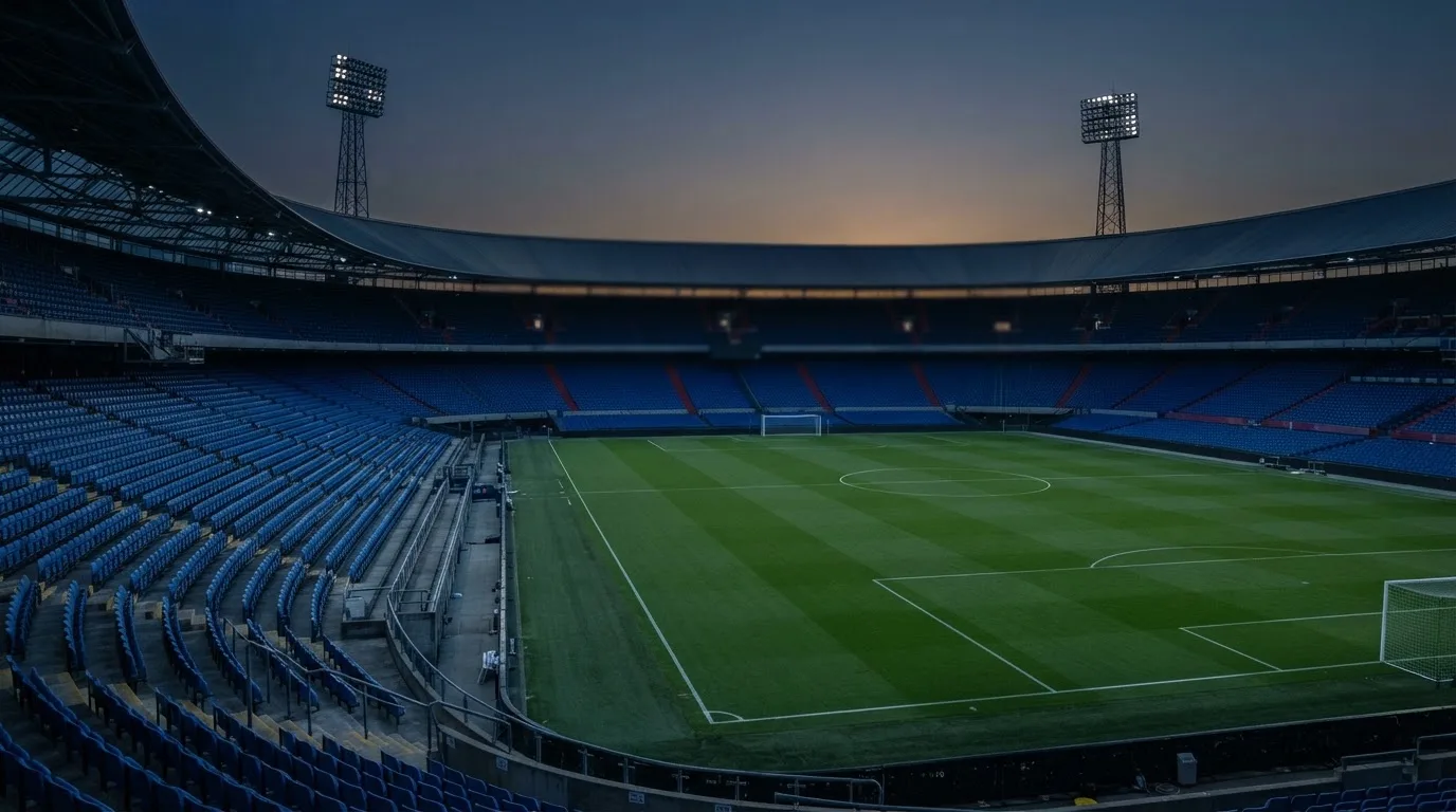 An empty football stadium with floodlight masts at dusk