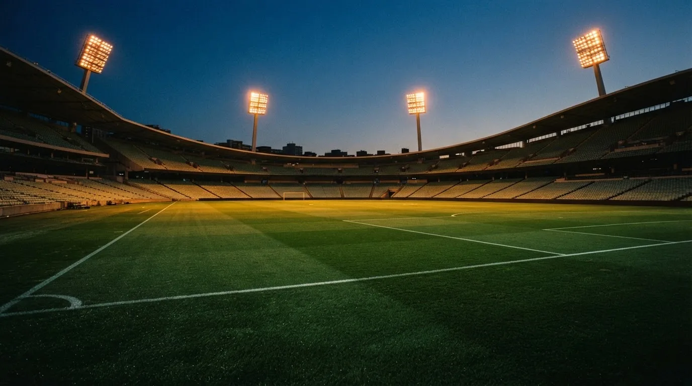 An empty football stadium with floodlight masts at dusk