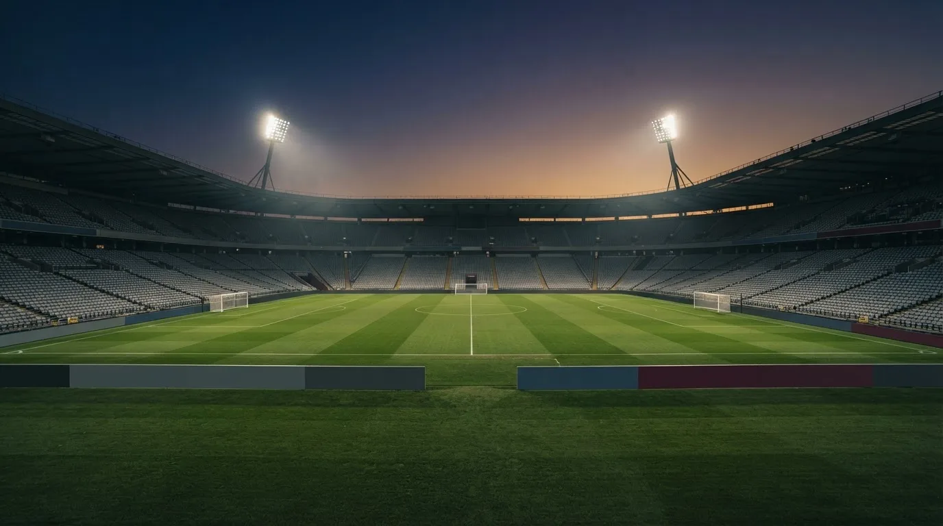 An empty football stadium with floodlight masts at dusk