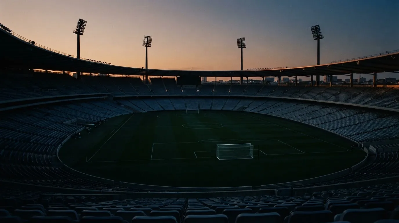 An empty football stadium with floodlight masts at dusk