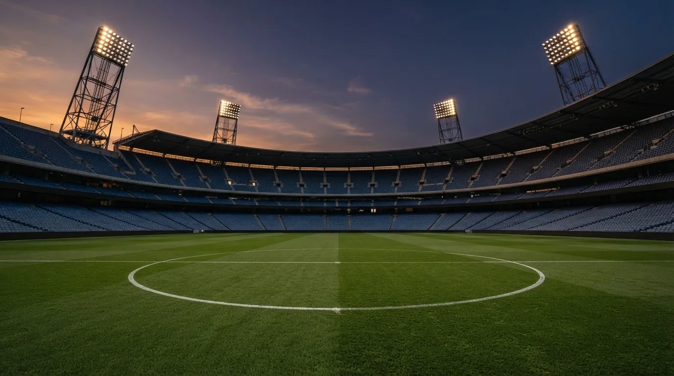 An empty football stadium with floodlight masts at dusk