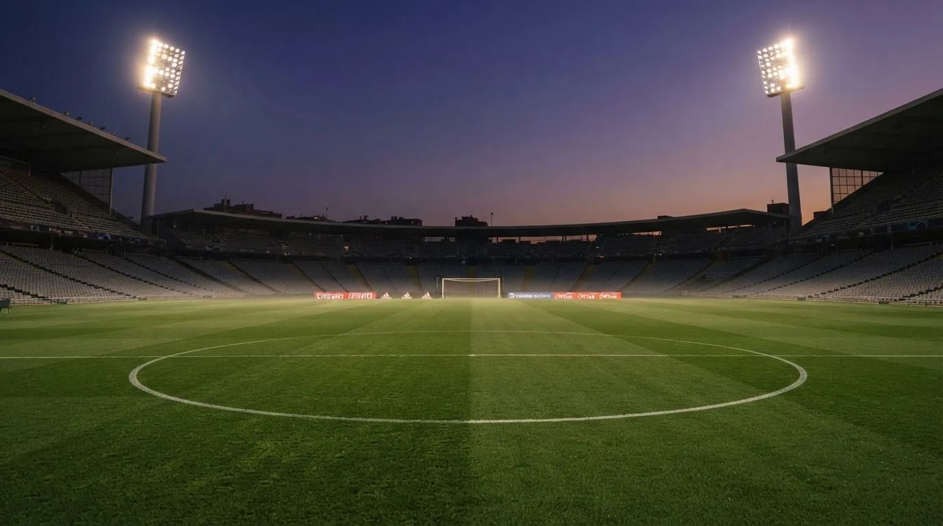 An empty football stadium with floodlight masts at dusk