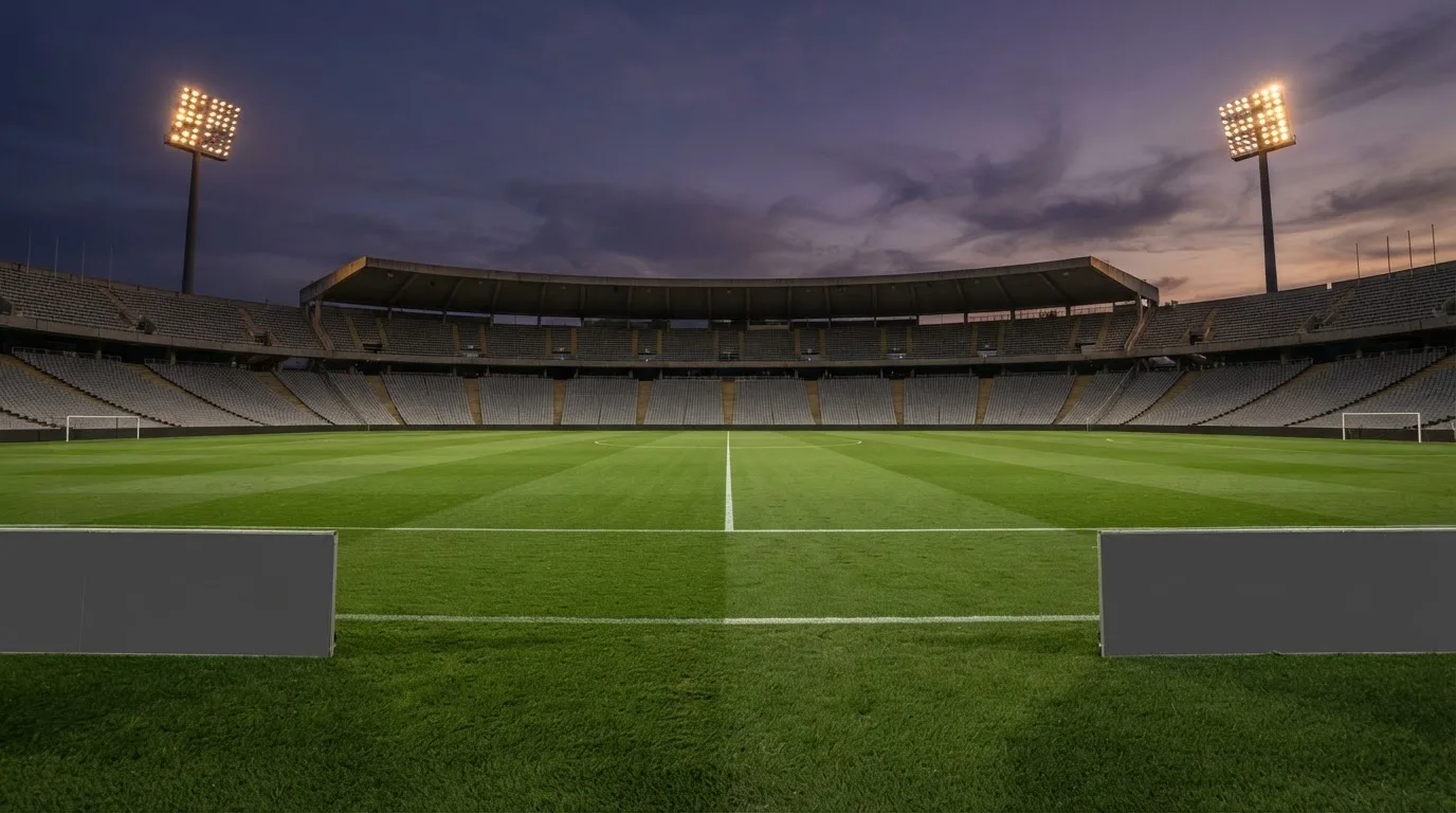 An empty football stadium with floodlight masts at dusk