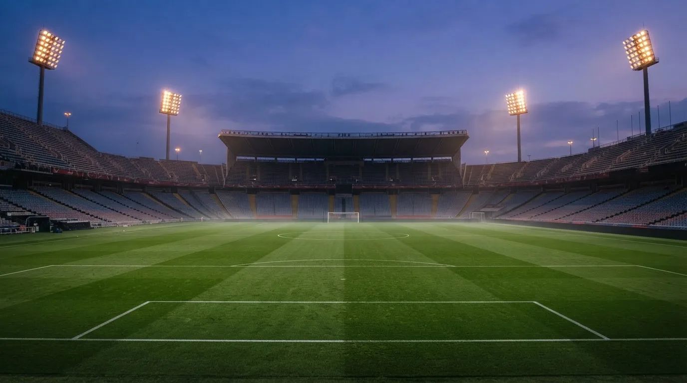 An empty football stadium with floodlight masts at dusk