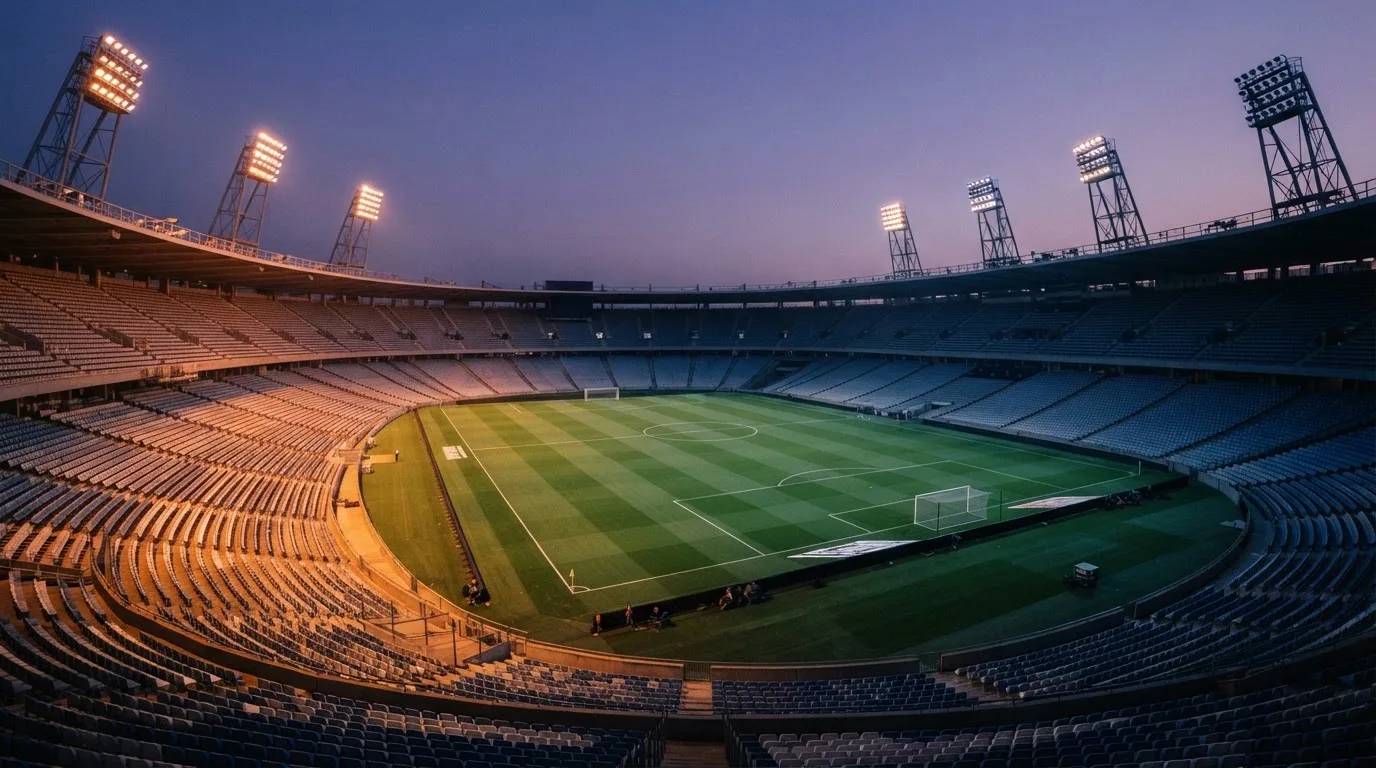 An empty football stadium with floodlight masts at dusk
