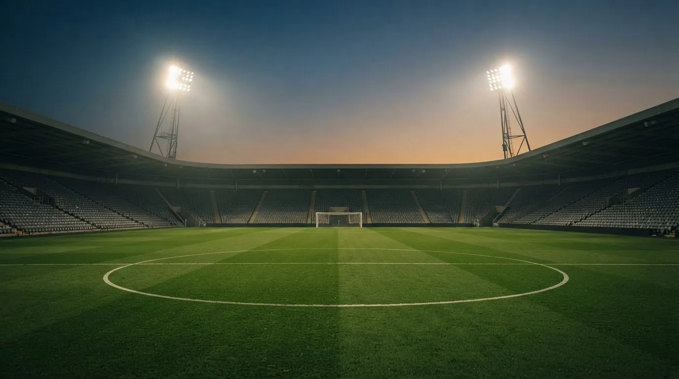 An empty football stadium with floodlight masts at dusk