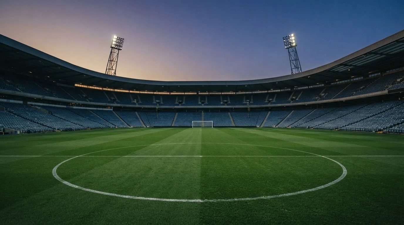 An empty football stadium with floodlight masts at dusk