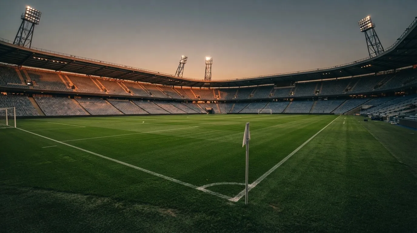 An empty football stadium with floodlight masts at dusk