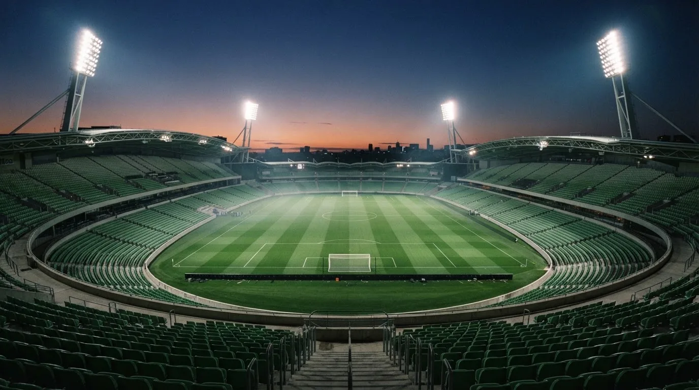 An empty football stadium with floodlight masts at dusk