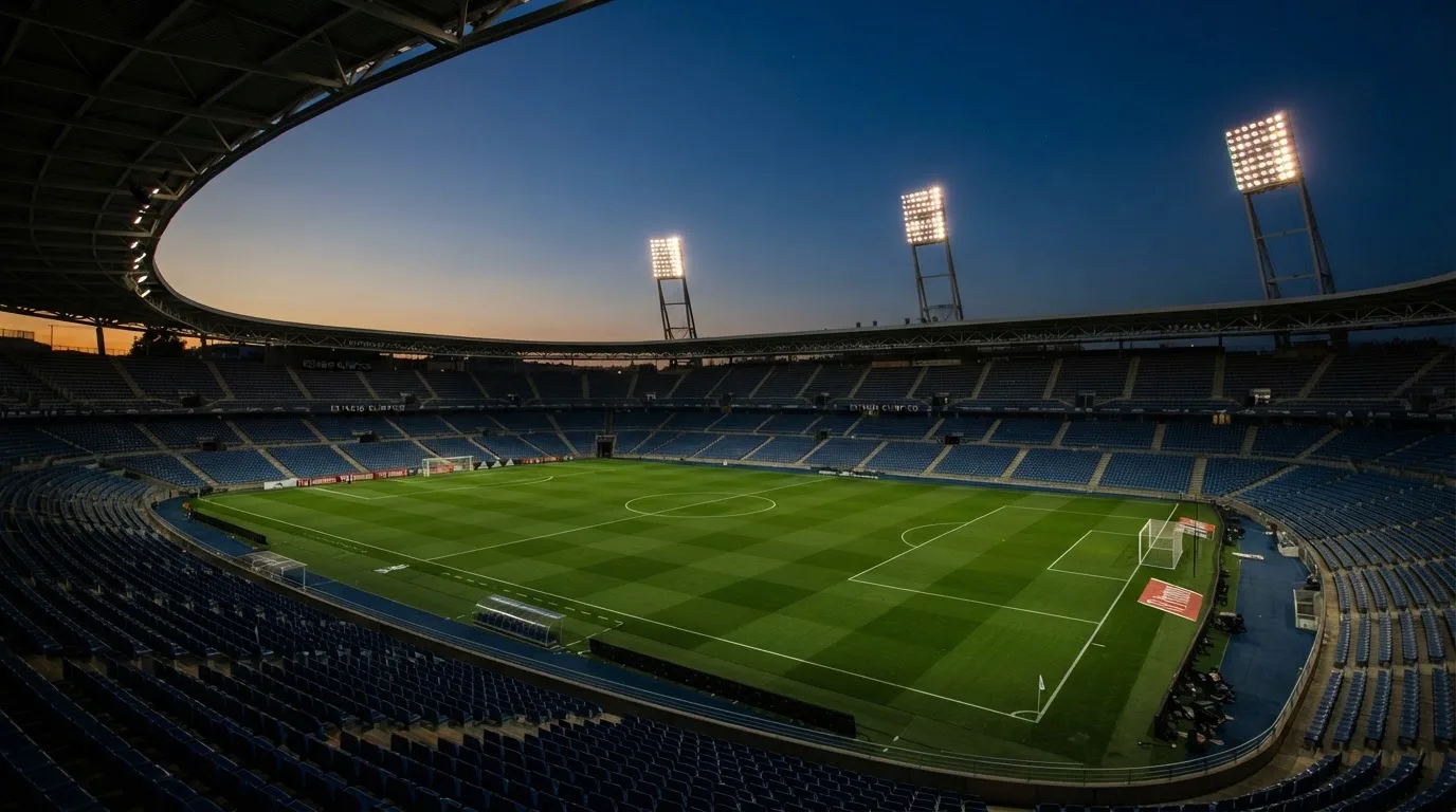 An empty football stadium with floodlight masts at dusk