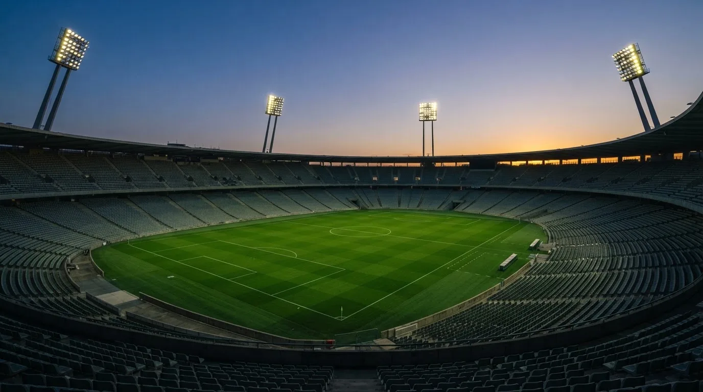 An empty football stadium with floodlight masts at dusk
