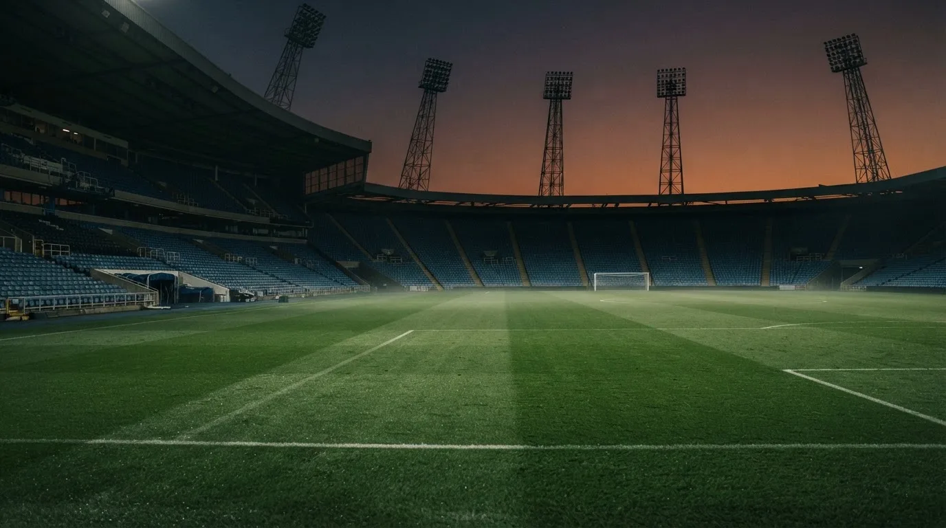 An empty football stadium with floodlight masts at dusk