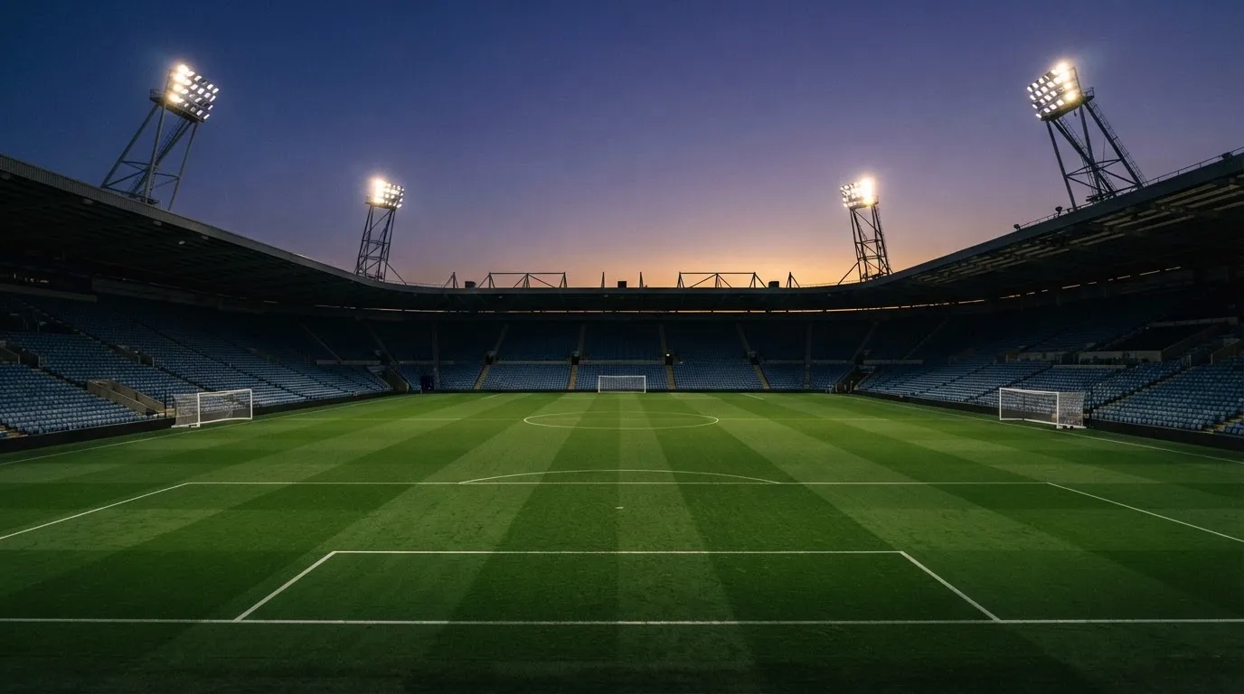 An empty football stadium with floodlight masts at dusk