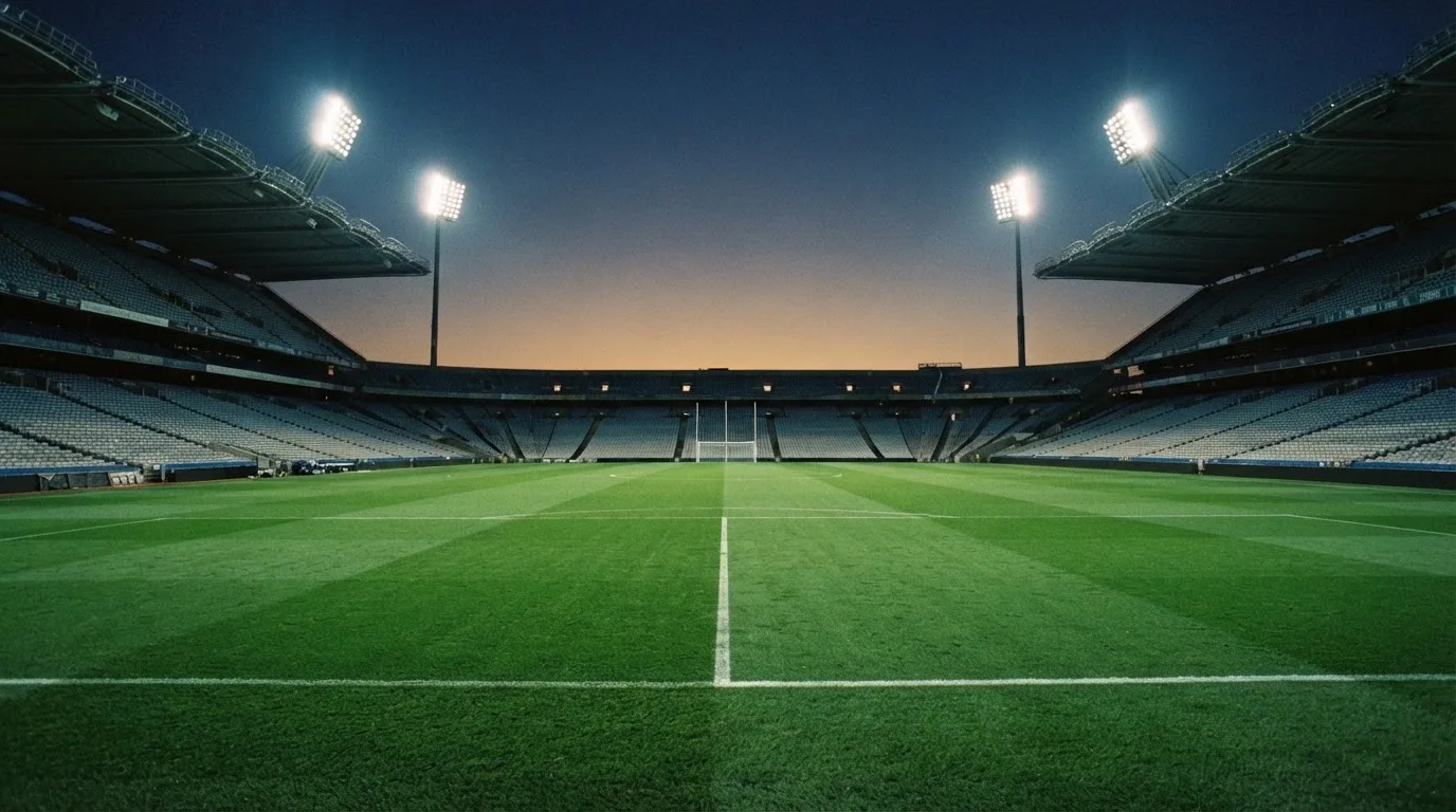 An empty football stadium with floodlight masts at dusk