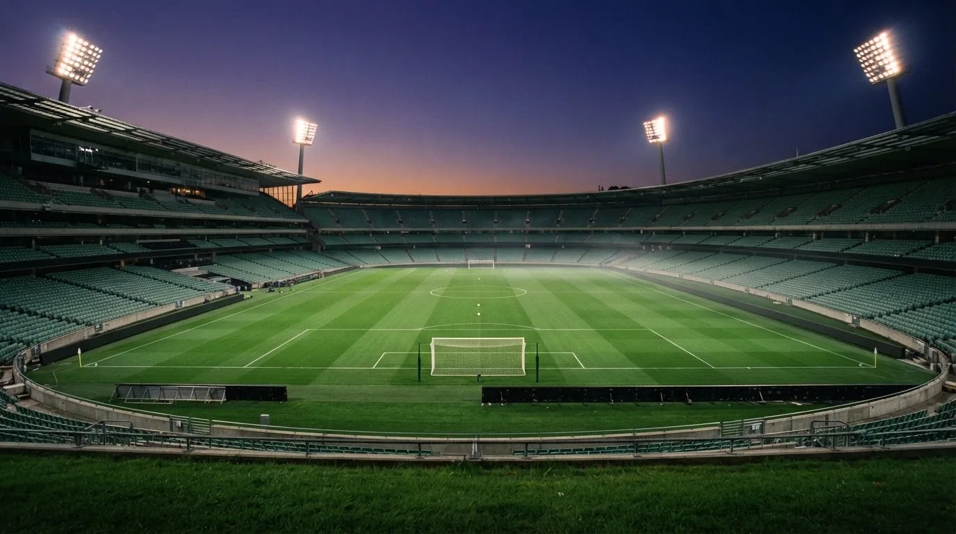 An empty football stadium with floodlight masts at dusk