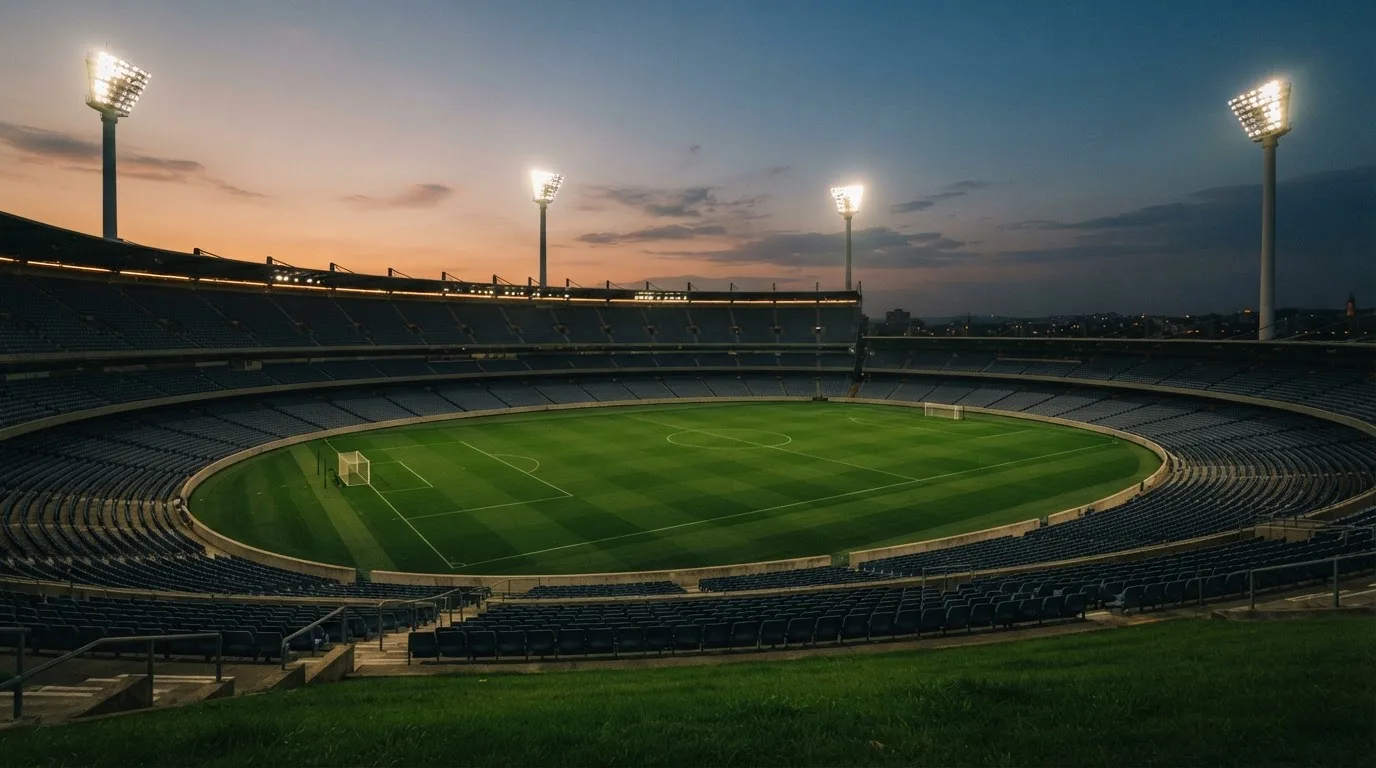 An empty football stadium with floodlight masts at dusk