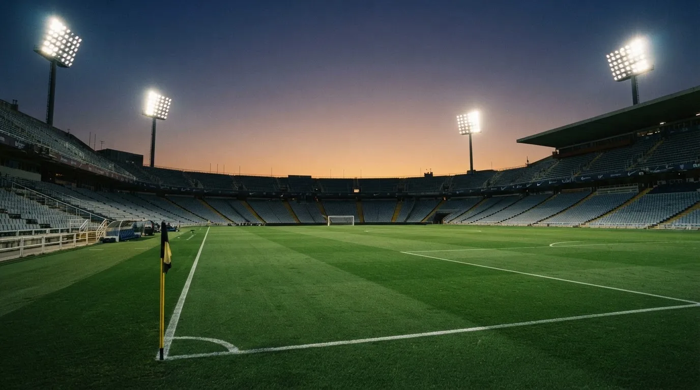 An empty football stadium with floodlight masts at dusk
