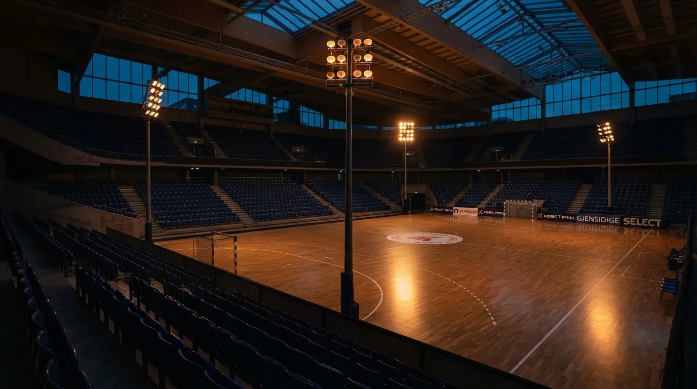 An empty football stadium with floodlight masts at dusk