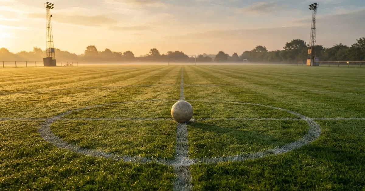 A ball on the centre spot of a grass pitch in morning light
