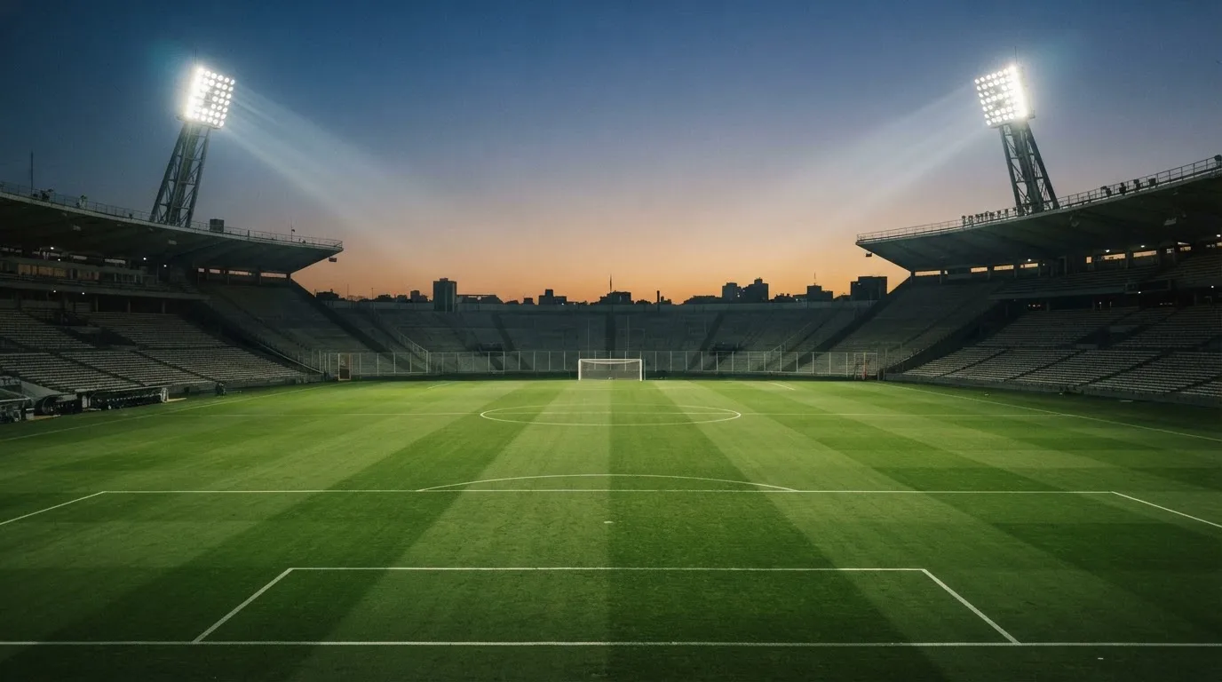 An empty football stadium with floodlight masts at dusk