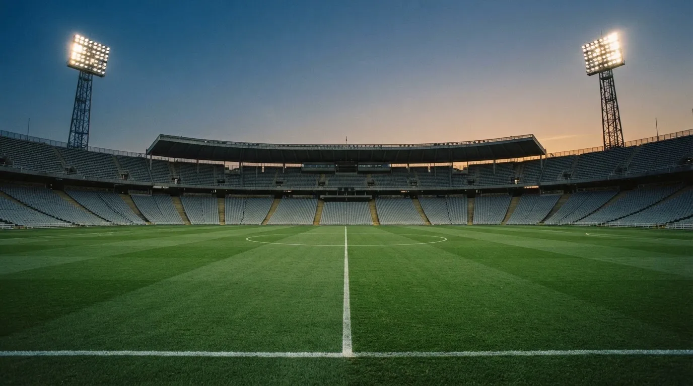 An empty football stadium with floodlight masts at dusk