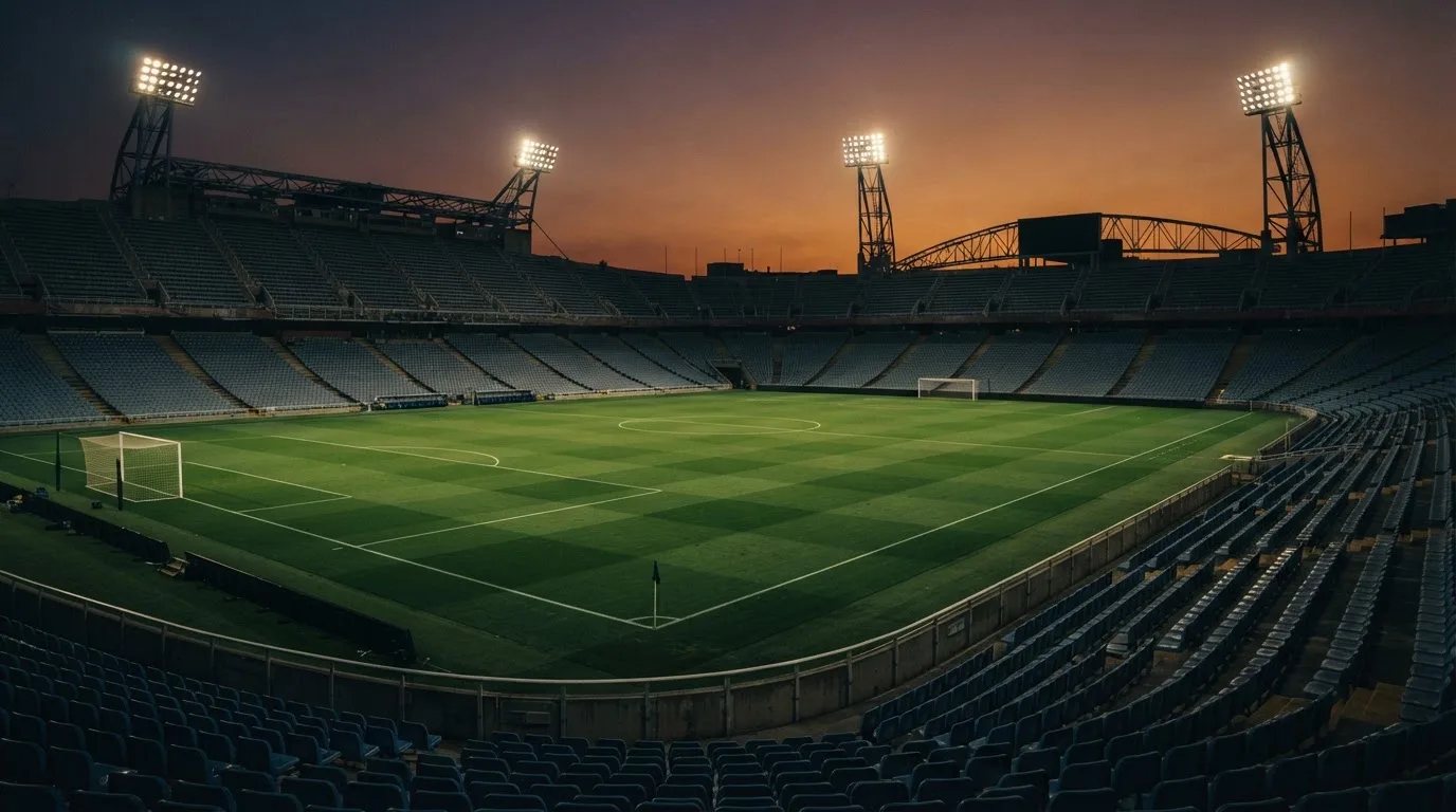 An empty football stadium with floodlight masts at dusk