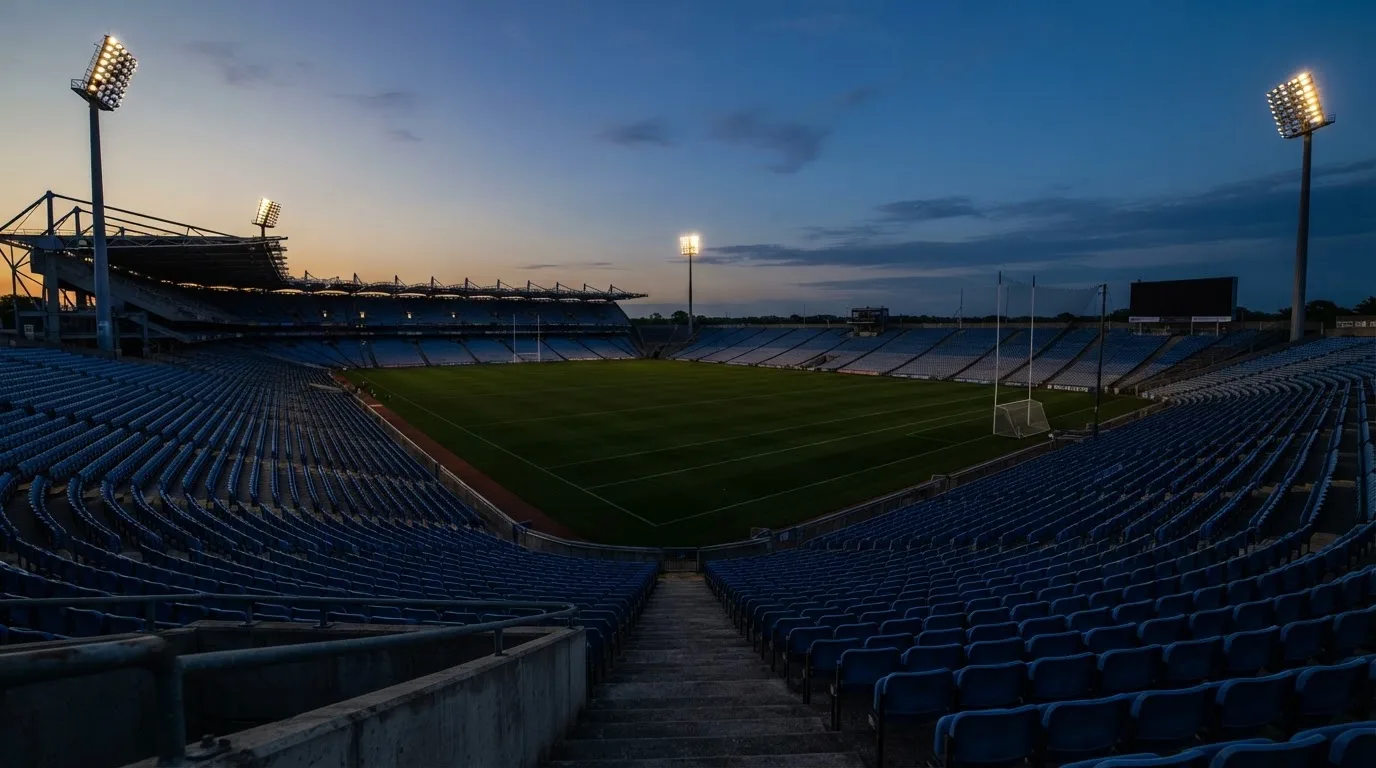 An empty football stadium with floodlight masts at dusk