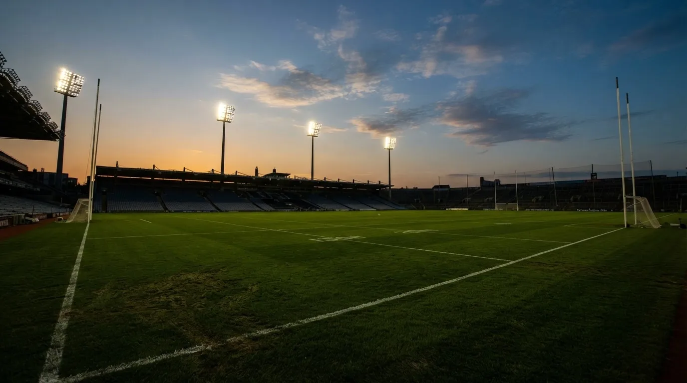 An empty football stadium with floodlight masts at dusk