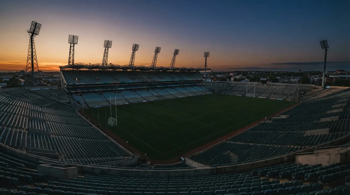 An empty football stadium with floodlight masts at dusk