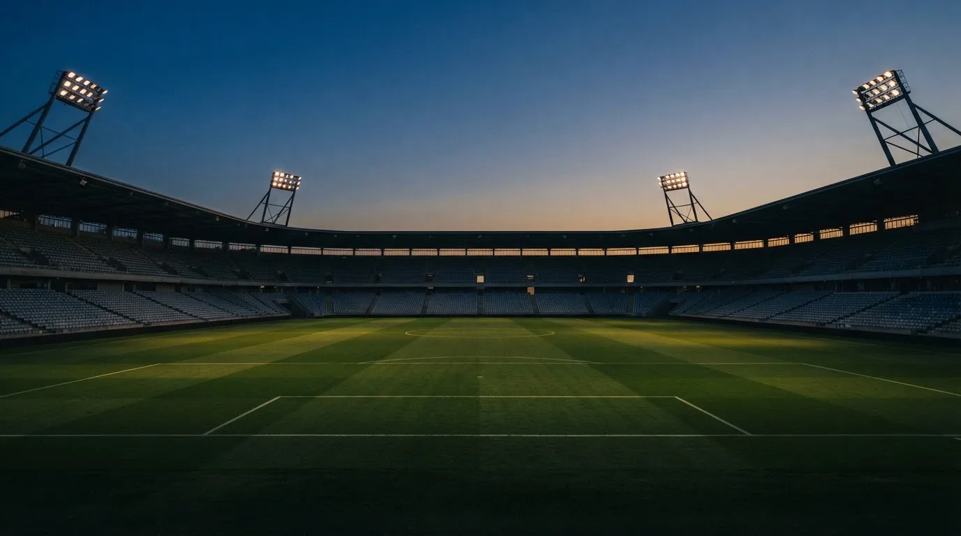 An empty football stadium with floodlight masts at dusk