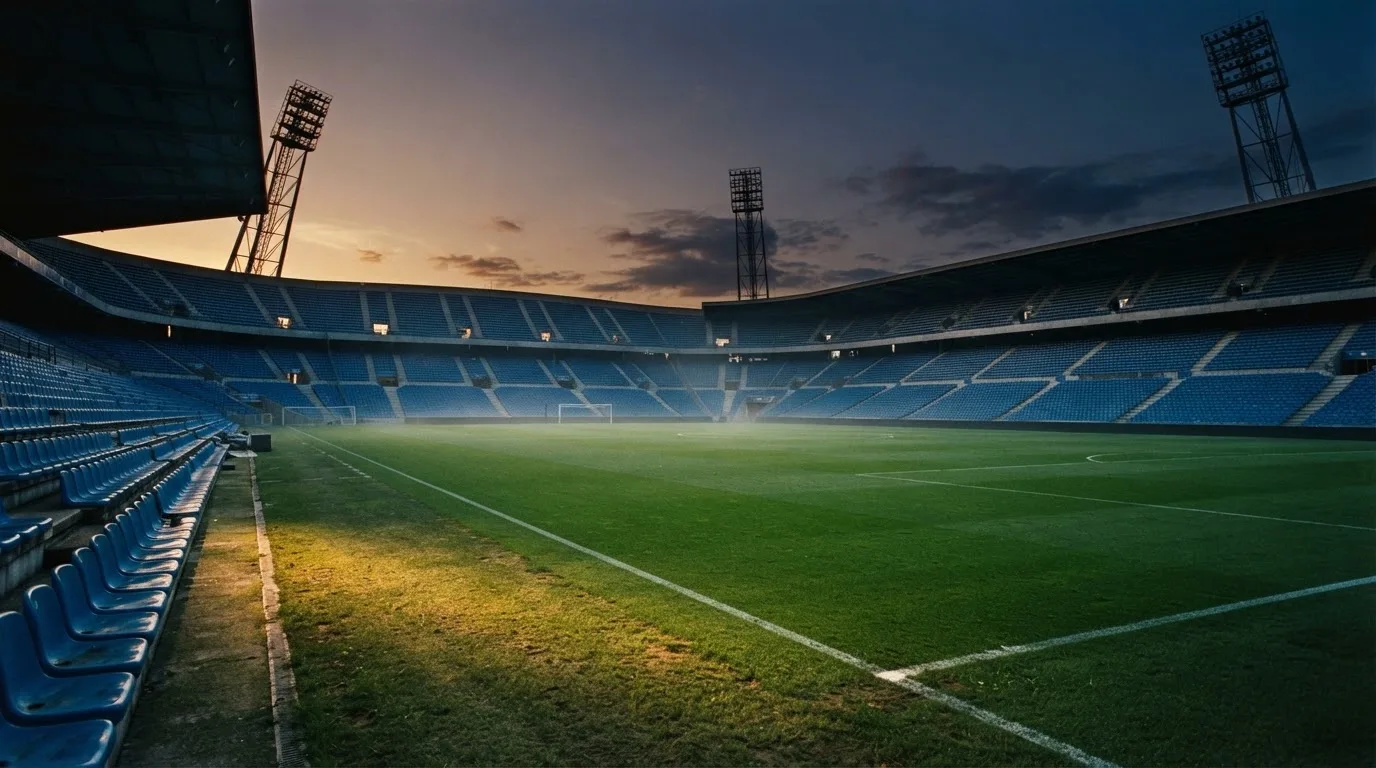 An empty football stadium with floodlight masts at dusk