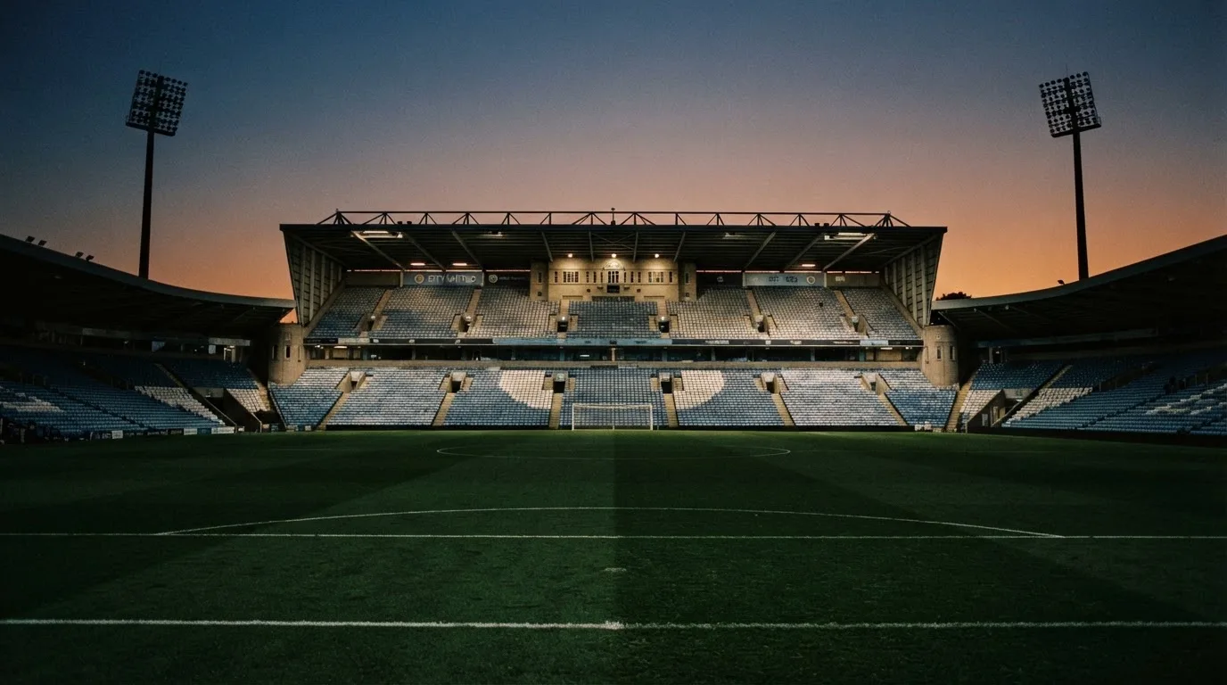 An empty football stadium with floodlight masts at dusk