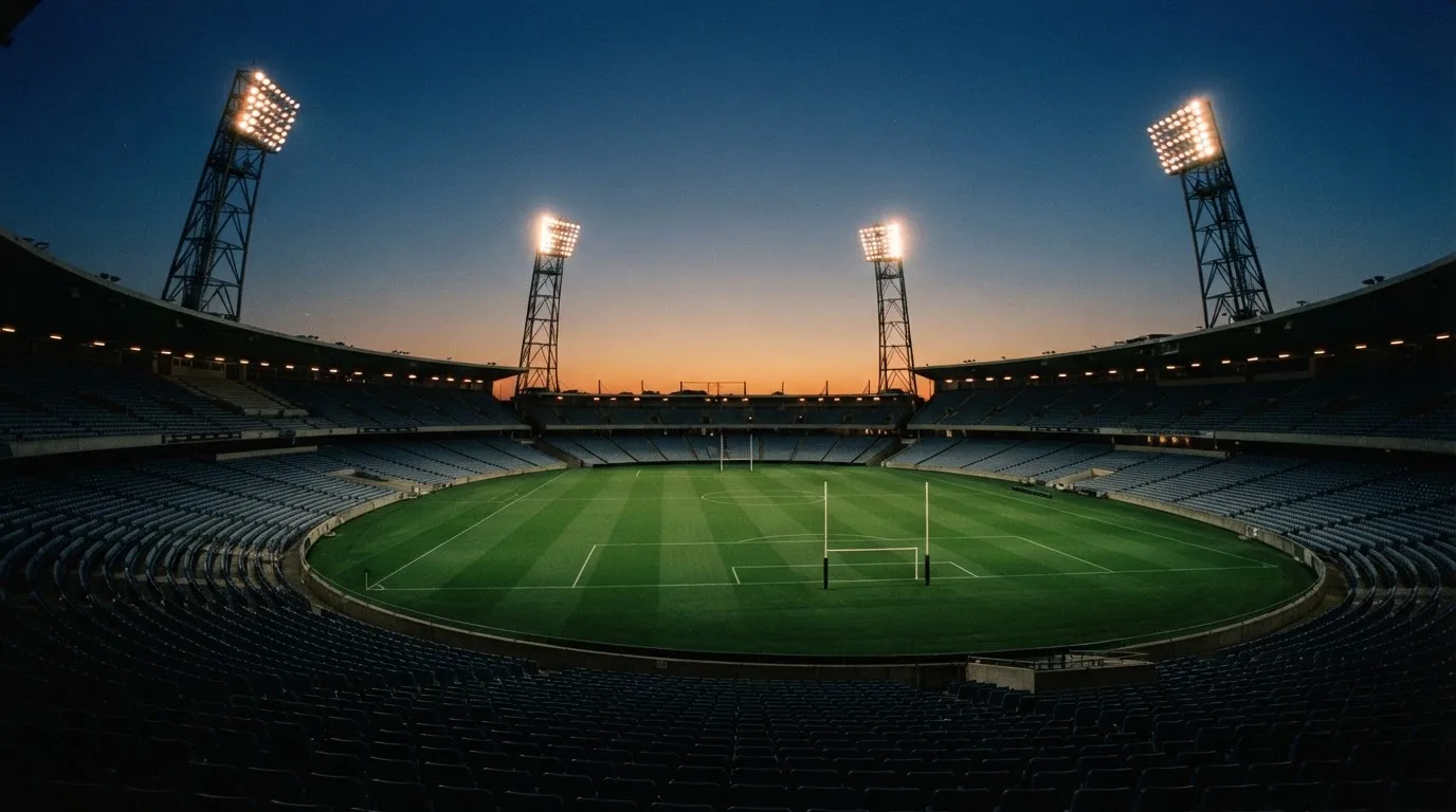 An empty football stadium with floodlight masts at dusk