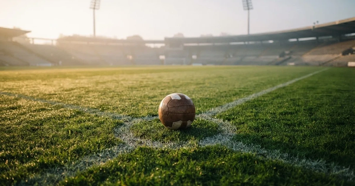A ball on the centre spot of a grass pitch in morning light