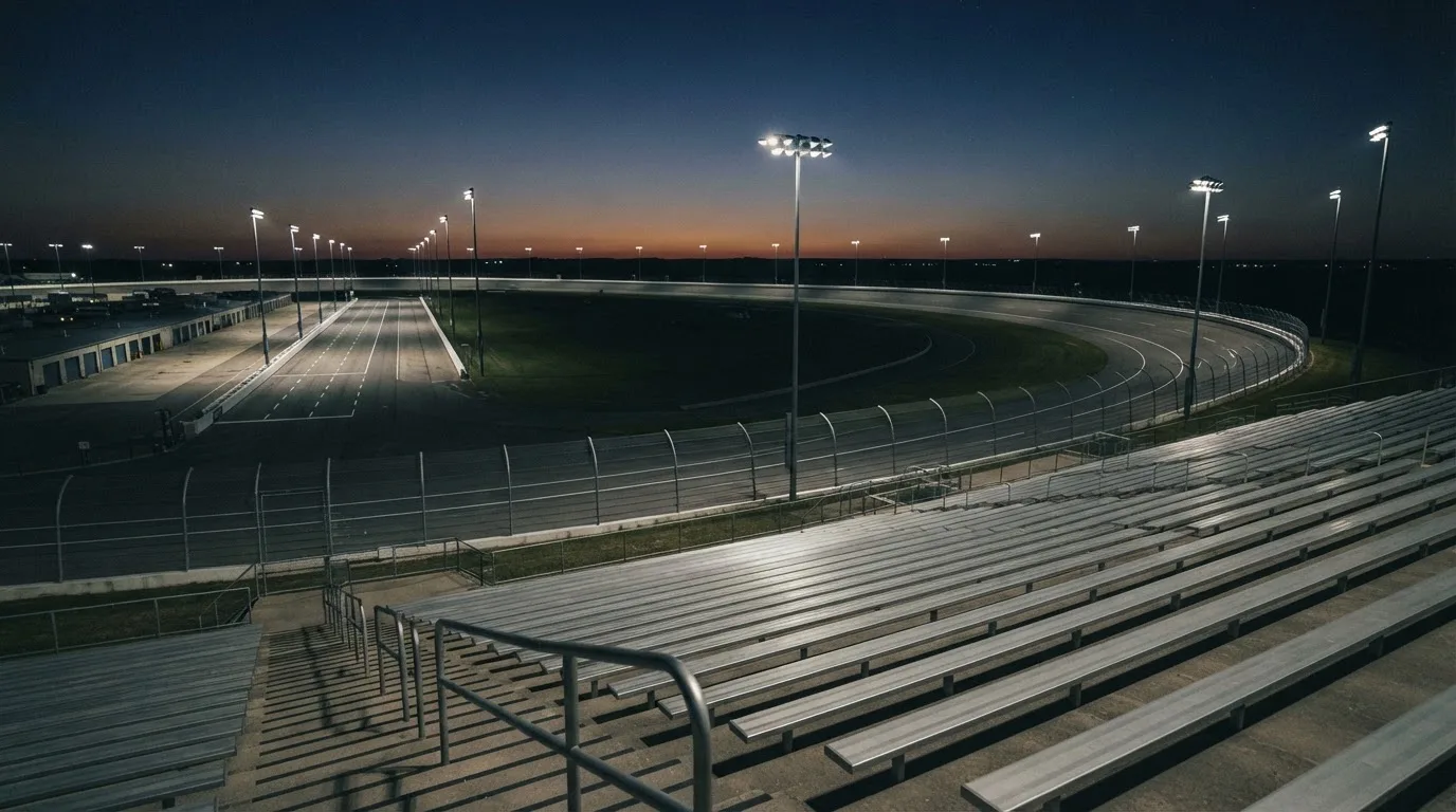 An empty football stadium with floodlight masts at dusk