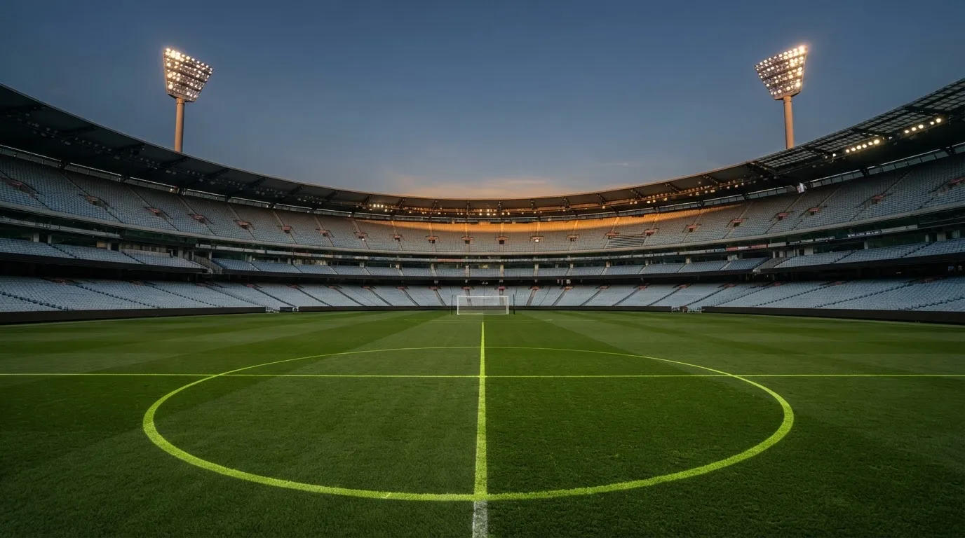 An empty football stadium with floodlight masts at dusk