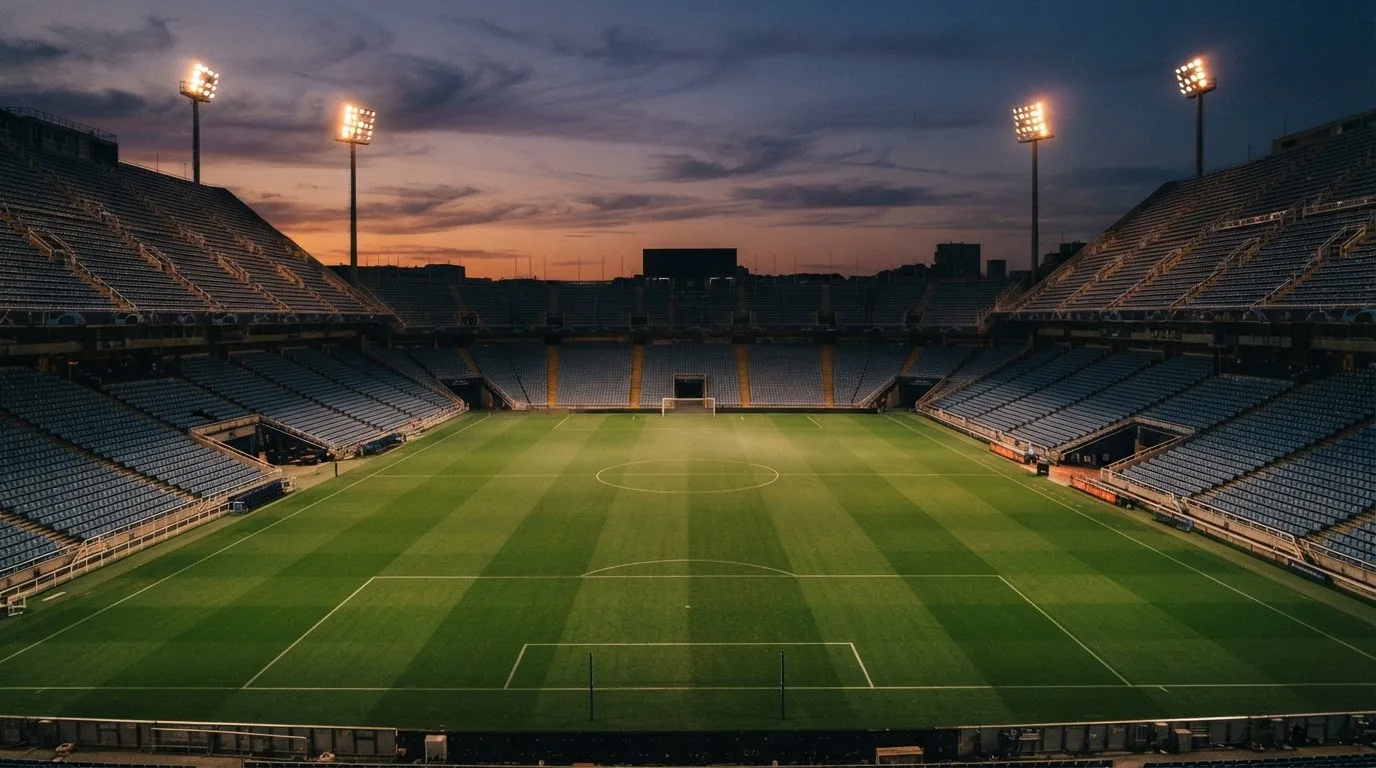 An empty football stadium with floodlight masts at dusk