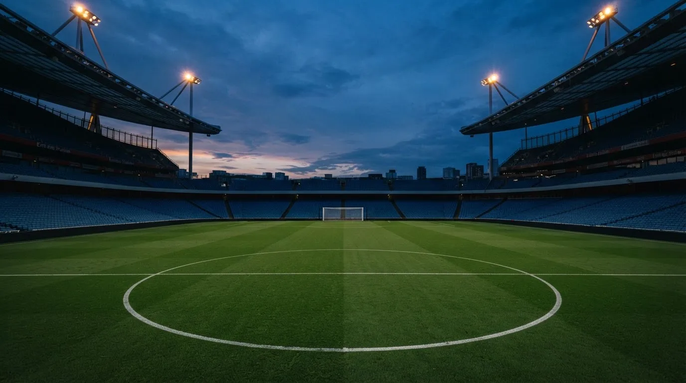 An empty football stadium with floodlight masts at dusk