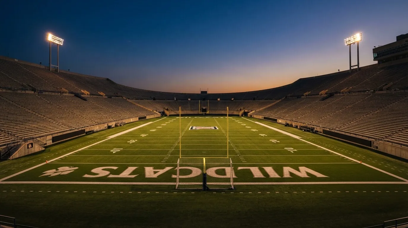An empty football stadium with floodlight masts at dusk