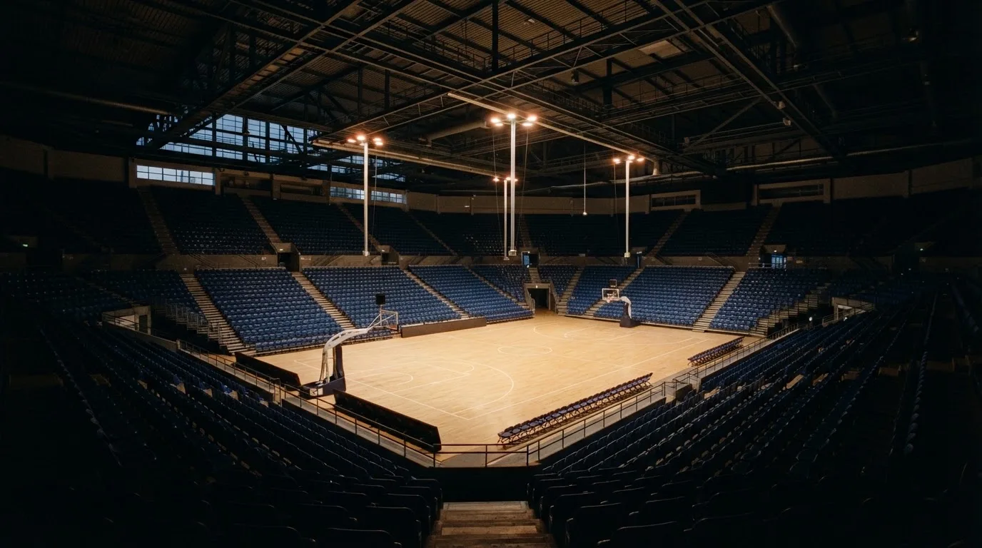 An empty football stadium with floodlight masts at dusk