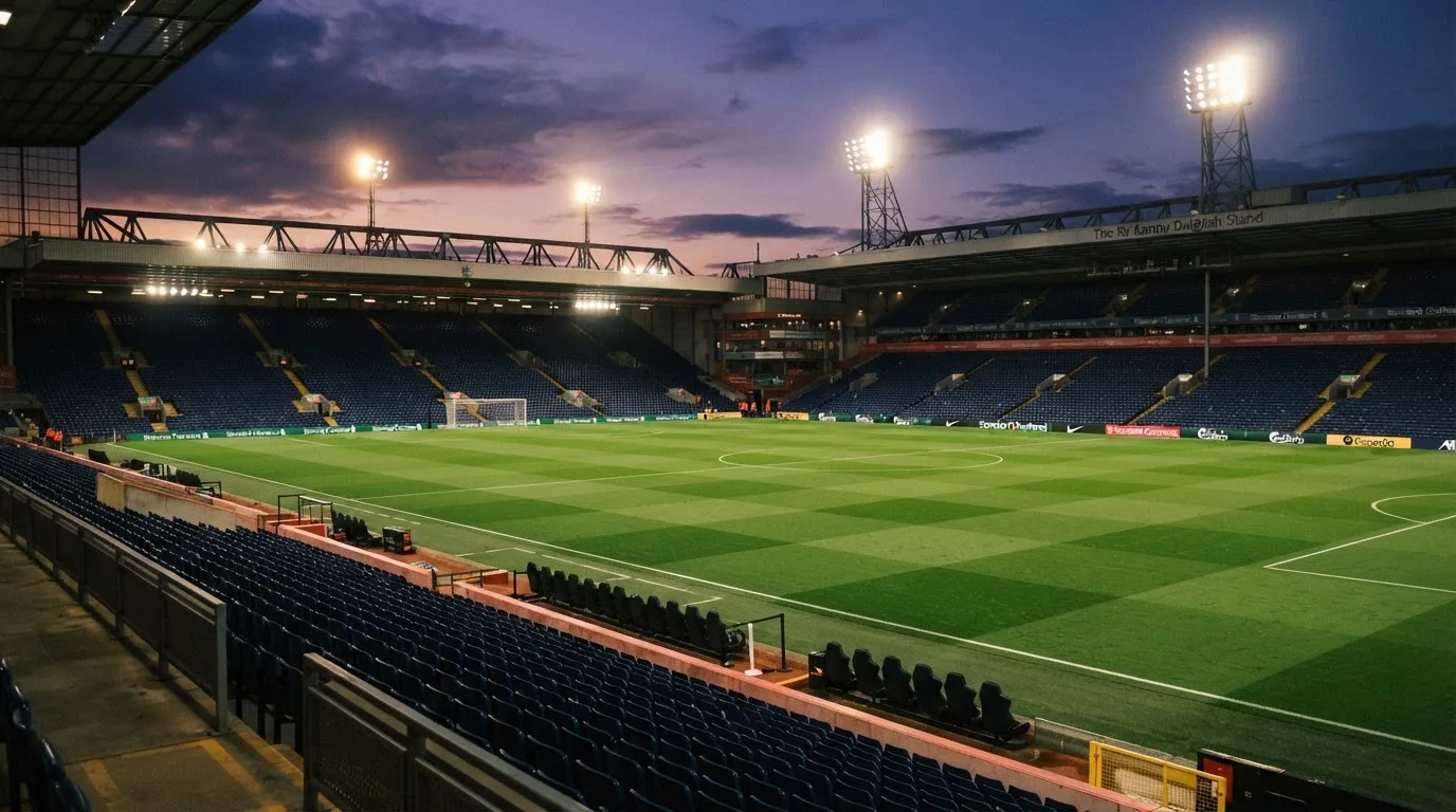 An empty football stadium with floodlight masts at dusk