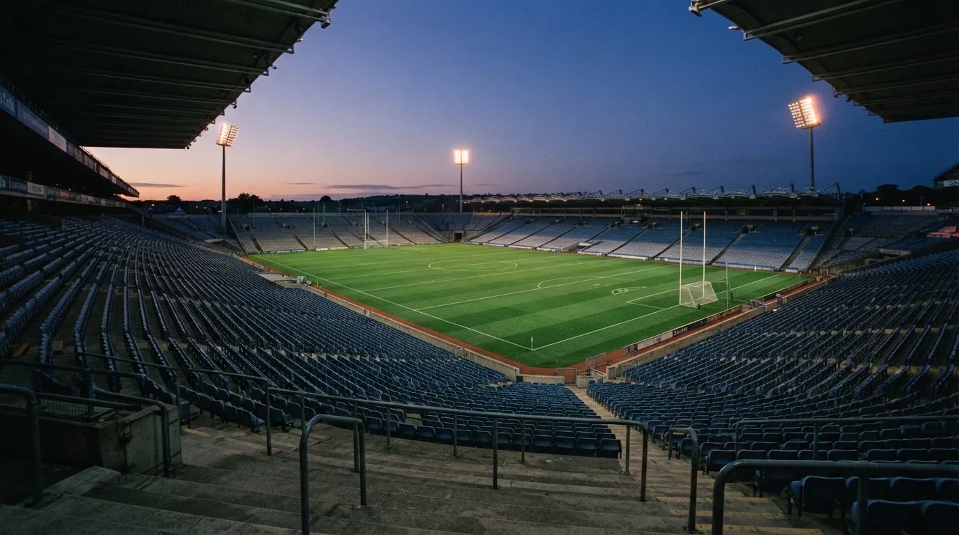 An empty football stadium with floodlight masts at dusk