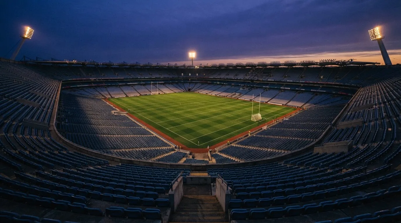 An empty football stadium with floodlight masts at dusk