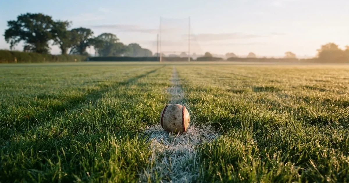 A ball on the centre spot of a grass pitch in morning light