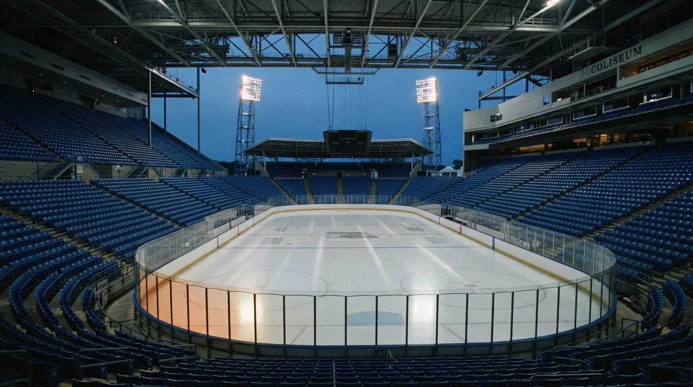 An empty football stadium with floodlight masts at dusk