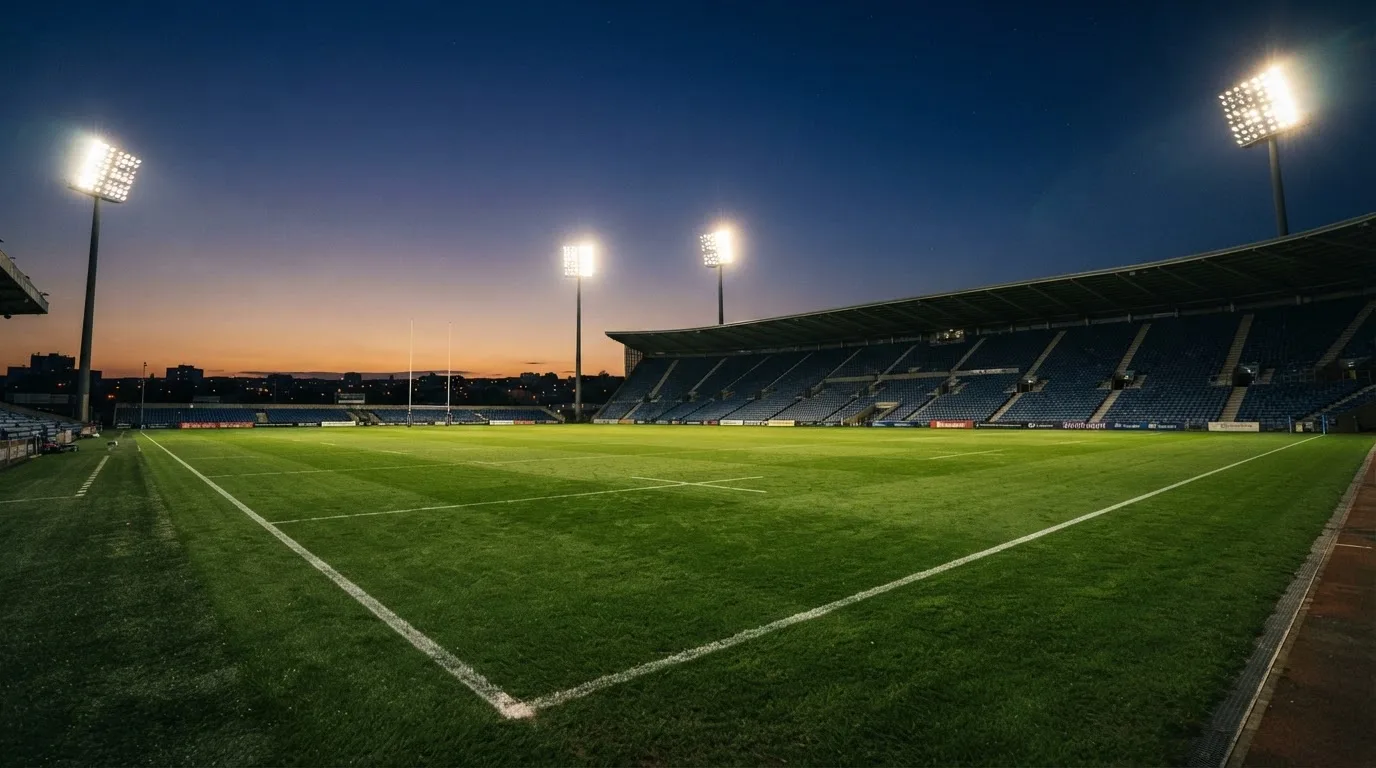 An empty football stadium with floodlight masts at dusk