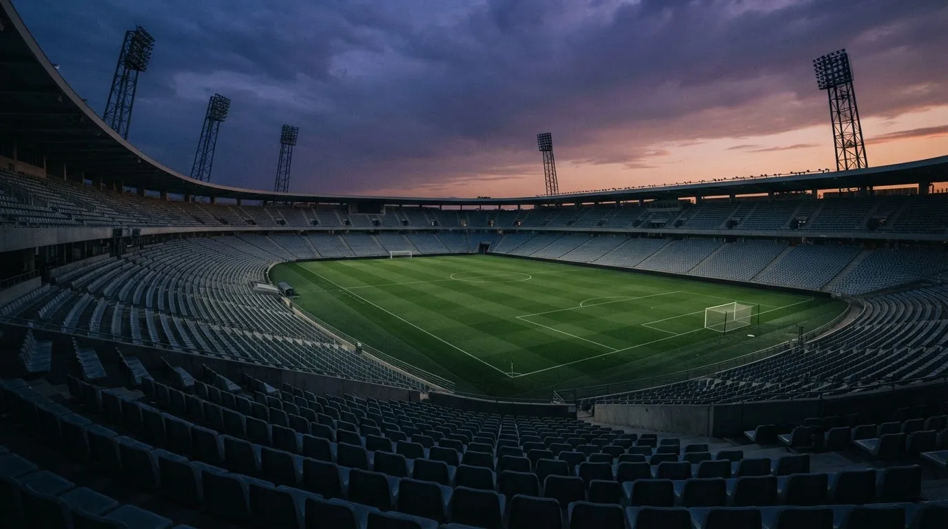 An empty football stadium with floodlight masts at dusk